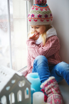 Little girl sitting on a window sill