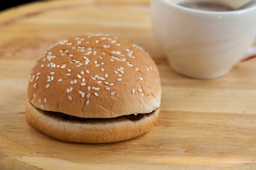 hamburgers and cup of black coffee on wooden board.