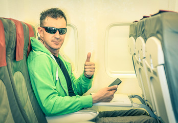 Hipster man passenger satisfied with thumbs up in airplane