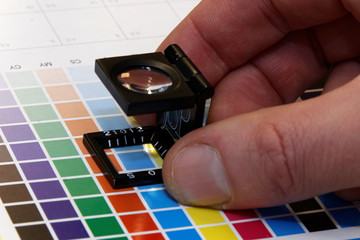 Close-up of a hand and a loupe on a test print