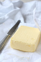 Piece of butter in paper with khife