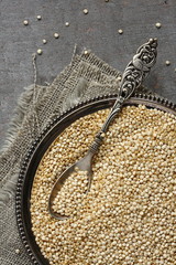 Uncooked quinoa in metal plate on wooden background