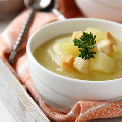 Creamy sweet potato soup with croutons and parsley in white bowl