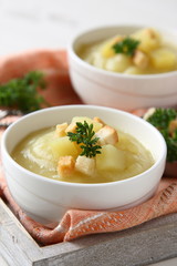 Bowl of creamy sweet potato soup with croutons on wooden tray