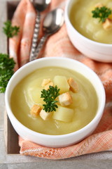 Creamy sweet potato soup with croutons and parsley in white bowl