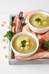 Bowl of creamy sweet potato soup with croutons on wooden tray