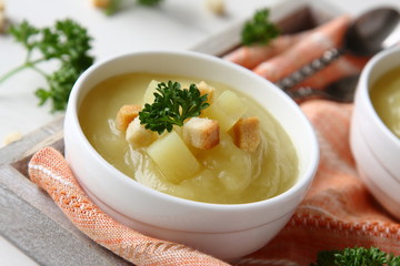 Creamy sweet potato soup with croutons and parsley in white bowl