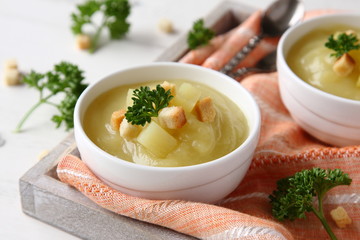 Bowl of creamy sweet potato soup with croutons on wooden tray