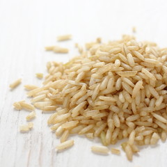 Pile of brown rice grain on white wooden background