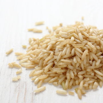 Pile of brown rice grain on white wooden background