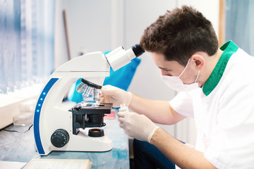 Naklejka na ściany i meble Scientist examining samples and working with microscope