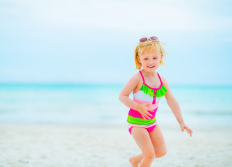 Baby girl in sunglasses playing on beach