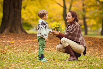 Little boy giving flowers to his mother