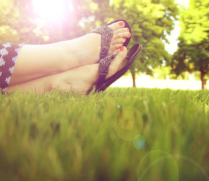 pretty feet on grass at sunset with nails painted and sandals on
