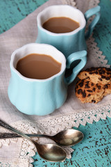 Cups of coffee with cookies and napkin on wooden table