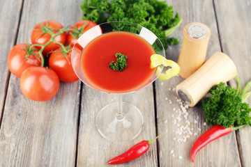 Tomato juice in goblet and fresh vegetables on wooden