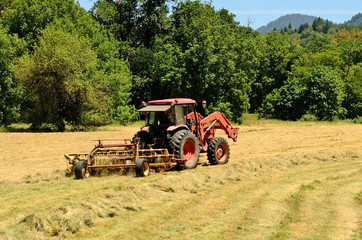 Naklejka premium Large Baler working a small farm field of grass hay