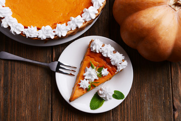 Piece of homemade pumpkin pie on plate on wooden background