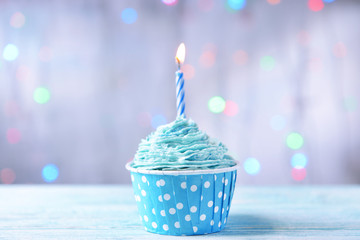 Delicious birthday cupcake on table on light background