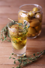 Green olives in oil with spices and rosemary in glass jars