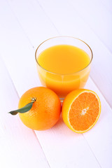 Glass of fresh orange juice on white wooden table