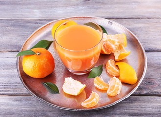 Glass of juice and ripe sweet tangerine on wooden table
