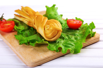Smoked braided cheese on wooden table