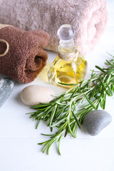 Branches of rosemary, towels and bottle with massage oil