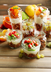 Healthy layered desserts with muesli and fruits on table