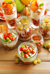 Fototapeta na wymiar Healthy layered desserts with muesli and fruits on table