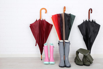 Bright umbrellas leaning against a bricks wall and gumboots