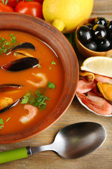 Tasty soup with shrimps, mussels, tomatoes and black olives in