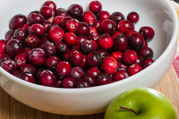 Bowl of cranberries with a green apple