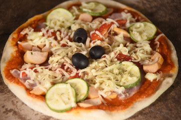 Cheese on a freshly prepared pizza on wooden board.