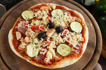 Cheese on a freshly prepared pizza on wooden board.