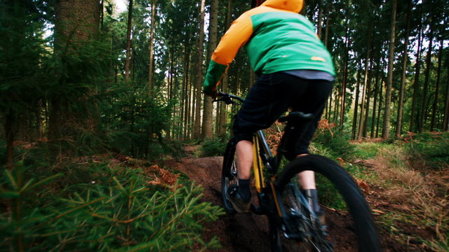 Man on mountain bike jumps in slow motion in woods