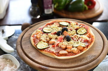 Cheese on a freshly prepared pizza on wooden board.