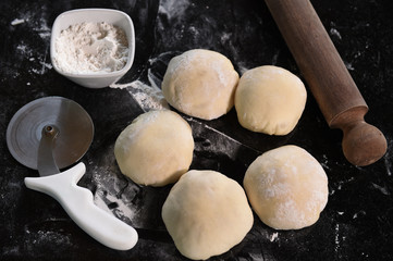 Small balls of fresh pizza dough on wooden board.