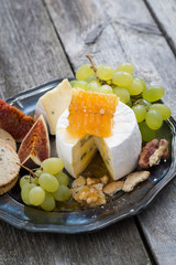fresh camembert with honey, grapes and crackers on plate