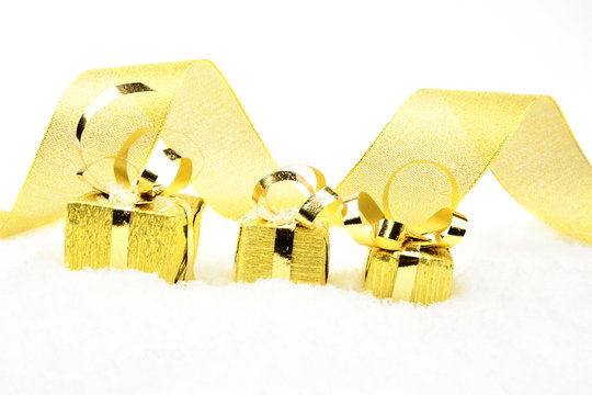 Golden christmas gifts in line with ribbon on snow