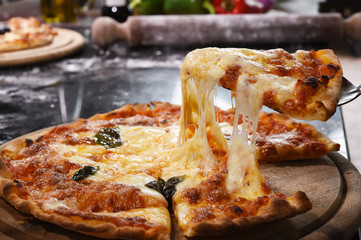 Pizza lifting slice on wooden board.