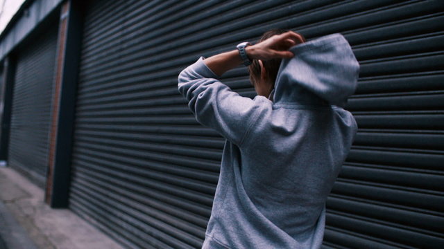 Woman putting on hoodie and starts running in urban area