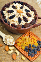 Oatmeal in ceramic plate, spoon, raisins, cashews and almonds on