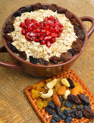 Oatmeal in ceramic plate, spoon, raisins, cashews and almonds.