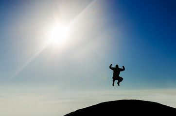 Silhouette of a happy man jumping on mountain top