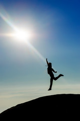 Man Silhouette jumping reaching the sun at the top of the world
