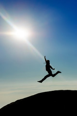 Silhouette man jumping toward sun