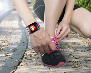 human hand tying shoelaces wearing bright pink watchband touchsc