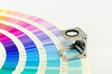 Magnifying glass standing on color guide on a white background