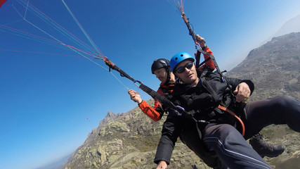 Tourist playing paragliding guided by a pilot